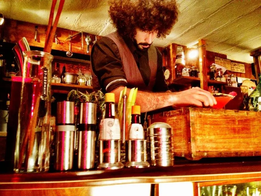 A bartender garnishing a cocktail behind the bar