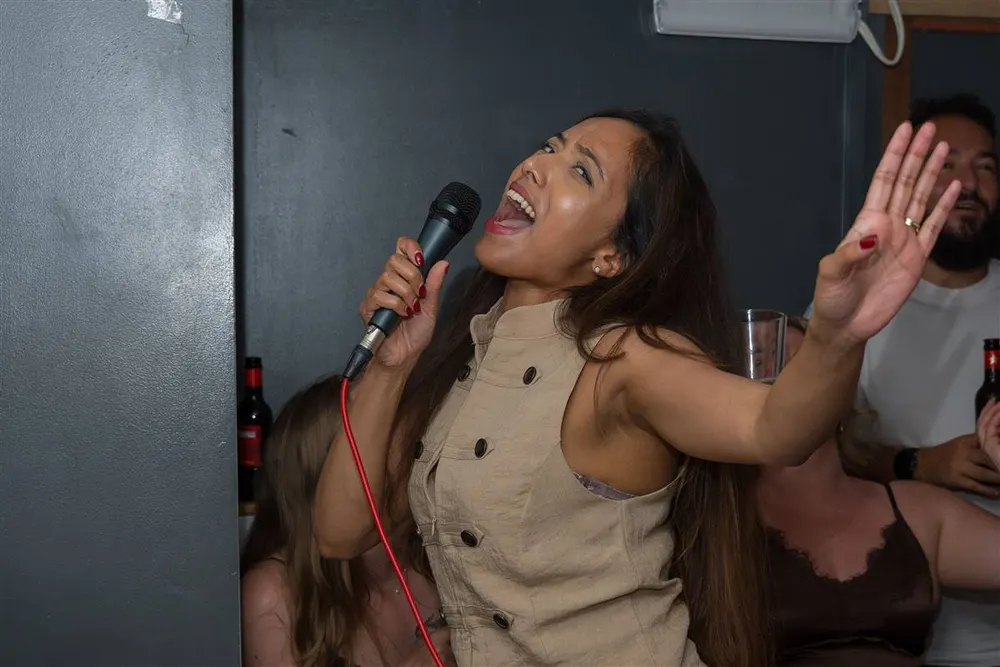 A singer with a hand raised in one of the private karaoke rooms